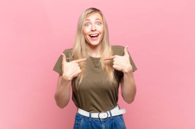 Genç sarışın güzel bir kadın mutlu, şaşırmış ve gururlu hissediyor, heyecanlı ve şaşkın bir bakışla kendini işaret ediyor.