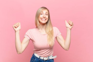 Genç, sarışın, güzel bir kadın son derece mutlu ve şaşırmış görünüyor, başarıyı kutluyor, bağırıyor ve zıplıyor.