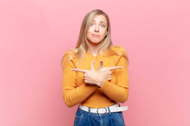 Genç, sarışın, kafası karışmış, güvensiz ve şüpheyle zıt yönlere bakan güzel bir kadın.