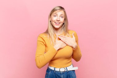 Genç sarışın güzel bir kadın romantik, mutlu ve aşık, neşeyle gülümseyen ve kalbe yakın el ele tutuşan