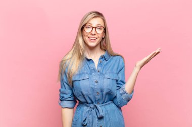 Genç sarışın güzel bir kadın mutlu, şaşırmış ve neşeli, pozitif bir tavırla gülümseyen, bir çözüm ya da fikir gerçekleştiren