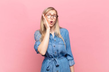 Sarışın, güzel bir kadın şok olmuş ve ağzı açık bir şekilde yüz yüze inanamamaktan şaşkına dönmüş durumda.