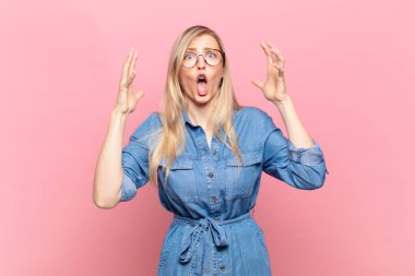 Genç, sarışın, güzel bir kadın ellerini havaya kaldırıp bağırıyor. Öfkeli, sinirli, stresli ve üzgün.