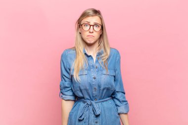 Genç sarışın, güzel bir kadın üzgün ve stresli. Kötü bir sürpriz yüzünden üzgün. Olumsuz ve endişeli bir bakışla.