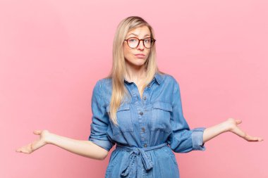 Genç sarışın güzel kadın kafası karışık ve kafası karışık, doğru cevap ya da karardan emin değil, seçim yapmaya çalışıyor.