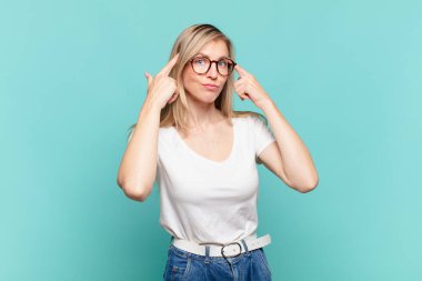 Genç, sarışın, güzel bir kadın. Kafası karışık ya da şüpheci. Bir fikre odaklanmış.