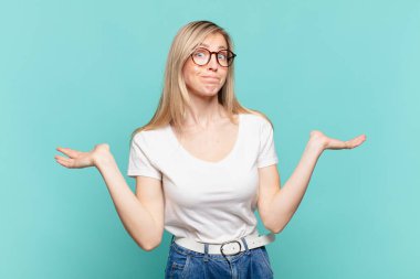 Genç sarışın güzel kadın şaşkın ve şaşkın hissediyor, şüpheci, ağırlıklı ya da farklı seçenekler seçiyor komik bir ifadeyle.