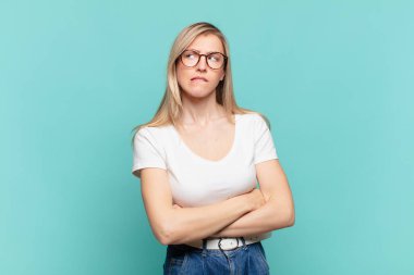 Genç sarışın, güzel bir kadın şüpheye düşüyor ya da düşünüyor, dudağını ısırıyor ve kendini güvensiz ve gergin hissediyor, kenarda yer arıyor.