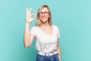 Genç sarışın güzel kadın mutlu, rahat ve tatmin olmuş hissediyor. Onayını iyi bir hareketle gösteriyor. Gülümsüyor.