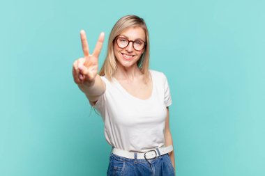 Genç sarışın güzel bir kadın gülümsüyor ve mutlu görünüyor, kaygısız ve pozitif, zafer ya da barışı simgeliyor.