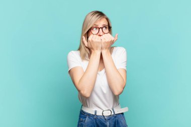 Genç sarışın güzel bir kadın endişeli, gergin, stresli ve korkmuş görünüyor tırnaklarını yiyor ve yanal fotokopi için yer arıyor.