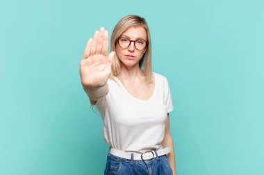 Genç sarışın güzel bir kadın ciddi, sert, hoşnutsuz ve kızgın görünüyor.