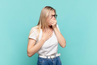 Gırtlağı ağrıyan ve grip belirtileri gösteren, ağzı kapalı öksüren genç sarışın güzel bir kadın.