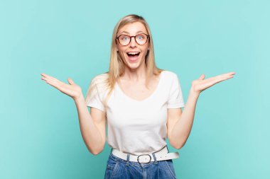 Genç sarışın güzel kadın mutlu, heyecanlı, şaşırmış ya da şok olmuş hissediyor, gülümsüyor ve hayrete düşüyor.