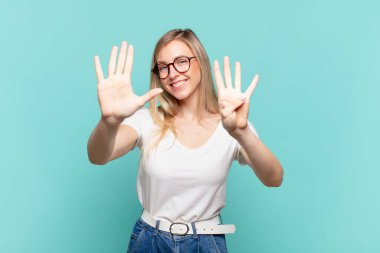 Genç sarışın güzel bir kadın gülümsüyor ve arkadaş canlısı görünüyor. 9 ya da 9 numarayı gösteriyor. Eli önde, geriye doğru sayıyor.