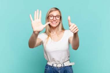 Genç sarışın güzel bir kadın gülümsüyor ve arkadaş canlısı görünüyor, altı ya da altıncı numarayı gösteriyor, eli önde, geri sayıyor.