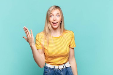 Genç sarışın güzel bir kadın mutlu, şaşırmış ve neşeli, pozitif bir tavırla gülümseyen, bir çözüm ya da fikir gerçekleştiren