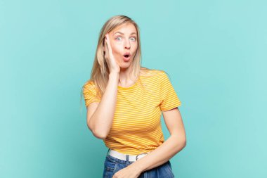 Sarışın, güzel bir kadın şok olmuş ve ağzı açık bir şekilde yüz yüze inanamamaktan şaşkına dönmüş durumda.