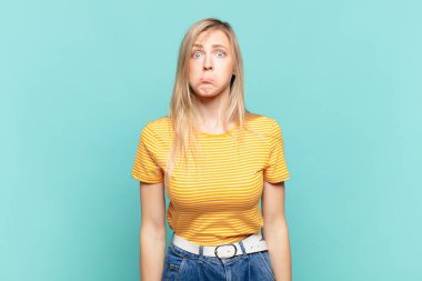 Genç sarışın, güzel bir kadın üzgün ve stresli. Kötü bir sürpriz yüzünden üzgün. Olumsuz ve endişeli bir bakışla.