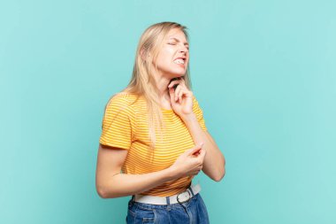 Genç sarışın güzel bir kadın stresli, hayal kırıklığına uğramış ve yorgun, endişeli ve sorunlu bir bakışla boynunu ovalıyor.