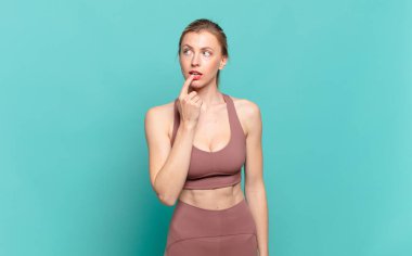 Şaşırmış, gergin, endişeli ya da korkmuş bakışları olan genç sarışın kadın fotokopi odasına bakıyor. spor konsepti