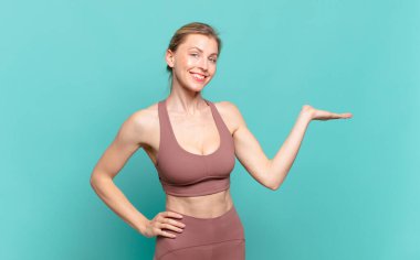 Genç sarışın kadın gülümsüyor, kendinden emin, başarılı ve mutlu hissediyor, fotokopi odasında konsept ya da fikir gösteriyor. spor konsepti