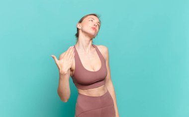 Genç sarışın kadın stresli, endişeli, yorgun ve hayal kırıklığına uğramış, gömleğini çekmiş, sorunlu görünüyor. spor konsepti