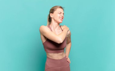 Genç sarışın kadın yorgun, stresli, endişeli, hayal kırıklığına uğramış ve depresyonda, sırtı ya da boynu ağrıyan. spor konsepti