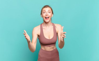 Genç sarışın kadın kendini mutlu, şaşkın, şanslı ve şaşırmış hissediyor. - İnanılmaz. spor konsepti