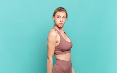 Şapşal, çılgın, şaşkın bir suratı olan, yanakları şişen, doldurulmuş, şişman ve yemek dolu genç sarışın bir kadın. spor konsepti