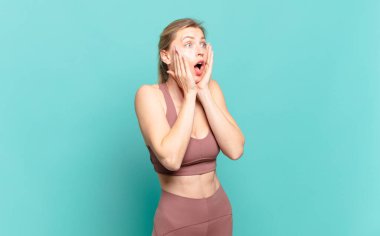 Genç sarışın kadın mutlu, heyecanlı ve şaşırmış hissediyor. İki eli yüzü de havada bir tarafa bakıyor. spor konsepti