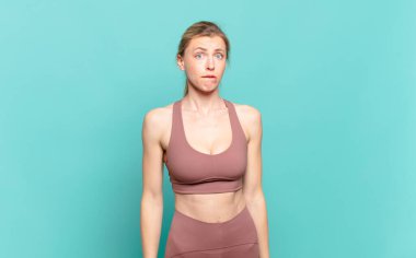 Genç sarışın kadın kendini cahil, kafası karışık ve hangi seçeneği seçeceği konusunda kararsız hissediyor. Sorunu çözmeye çalışıyor. spor konsepti