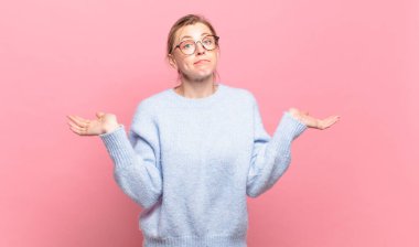 Genç, güzel sarışın kadın şaşkın ve şaşkın hissediyor. Şüpheci, ağırlıklı ya da farklı seçenekleri komik bir ifadeyle seçiyor.