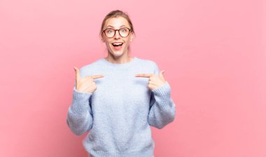 Genç, güzel, sarışın, mutlu, şaşkın ve gururlu bir kadın. Heyecanlı ve şaşkın bir bakışla kendini işaret ediyor.