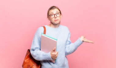 Genç güzel öğrenci şaşkın ve şaşkın hissediyor, şüpheci, farklı seçenekleri tartıyor veya komik bir ifadeyle seçiyor.