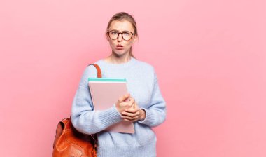 Genç ve güzel bir öğrenci şaşkın ve şaşkın hissediyor. Beklenmedik bir şeye bakan aptal, afallamış bir ifadeyle.