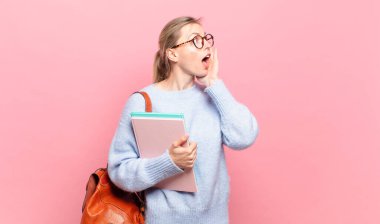 Genç ve güzel bir öğrenci, mutlu, heyecanlı ve şaşırmış hissediyor, iki eli yüzü yana bakıyor.