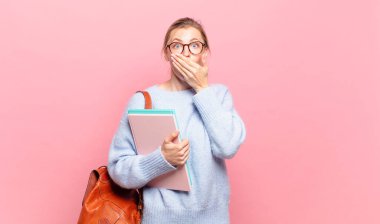 Şok olmuş, şaşırmış bir ifadeyle ağzını kapatan genç ve güzel bir öğrenci. Sır saklıyor ya da 