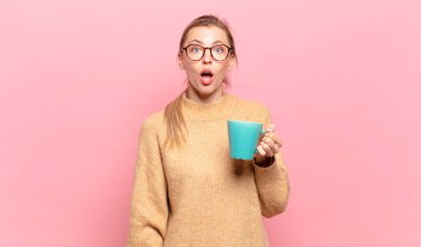 Genç sarışın kadın şok olmuş ya da şaşırmış görünüyor, ağzı açık bir şekilde 