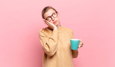 Genç sarışın kadın, sıkıcı, sıkıcı ve sıkıcı bir işten sonra sıkılmış, hayal kırıklığına uğramış ve uykulu hissediyor. kahve konsepti