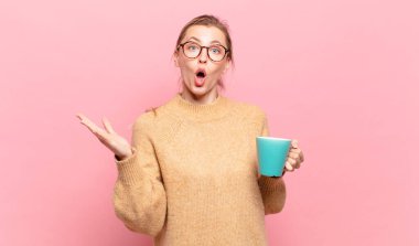 Genç sarışın kadın şok olmuş ve şaşırmış, endişeli ve paniklemiş, stresli ve dehşete kapılmış görünüyor. kahve konsepti