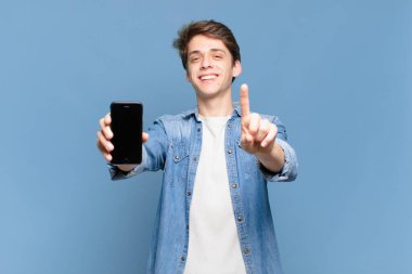 Gururla gülümseyen ve kendine güveni tam bir lider gibi poz veren genç bir çocuk. telefon kavramı