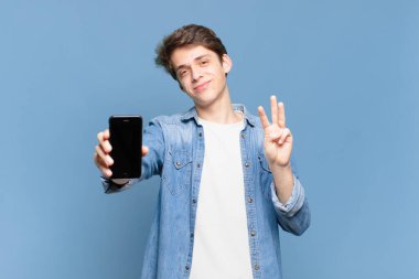 Genç çocuk gülümsüyor ve arkadaş canlısı görünüyor, üç ya da üç numarayı gösteriyor, eli önde, geri sayıyor. telefon kavramı