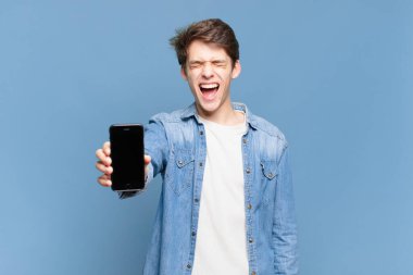 Genç çocuk agresif bir şekilde bağırıyor, çok kızgın, sinirli, öfkeli ya da sinirli görünüyor, hayır diye bağırıyor. telefon kavramı