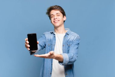 Genç çocuk mutlu bir şekilde gülümsüyor, mutlu hissediyor ve fotokopi uzayı içinde avucunun içi gibi bir konsept gösteriyor. telefon kavramı