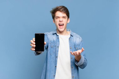 Genç çocuk sinirli, sinirli ve hayal kırıklığına uğramış görünüyor. Senin neyin var? telefon kavramı 
