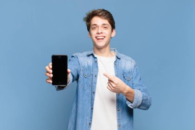 Genç çocuk heyecanlı ve şaşırmış görünüyor. Yana ve yukarı doğru uzayı işaret ediyor. telefon kavramı