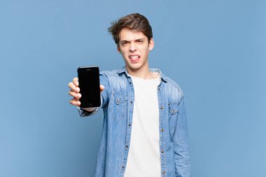Delikanlı tiksinmiş ve rahatsız olmuş hissediyor. Dilini dışarı çıkarıyor. İğrenç ve iğrenç bir şeyden hoşlanmıyor. telefon kavramı