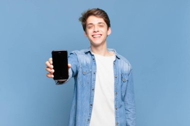 Genç çocuk mutlu ve hoş bir şekilde şaşırmış görünüyor. Büyülenmiş ve şok olmuş bir ifadeyle heyecanlanıyor. telefon kavramı