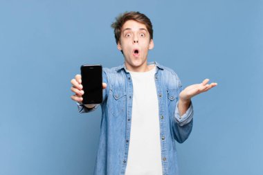 Delikanlı kendini son derece şok olmuş, şaşırmış, endişeli ve paniklemiş hissediyor. Stresli ve dehşete düşmüş bir bakışı var. telefon kavramı